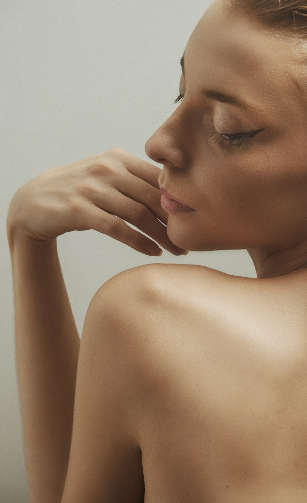 Femme de profil, épaule nue, main portée au visage