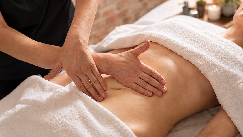 Mains massant le ventre d'une femme allongée sous une serviette, soin Drainage de Biostem