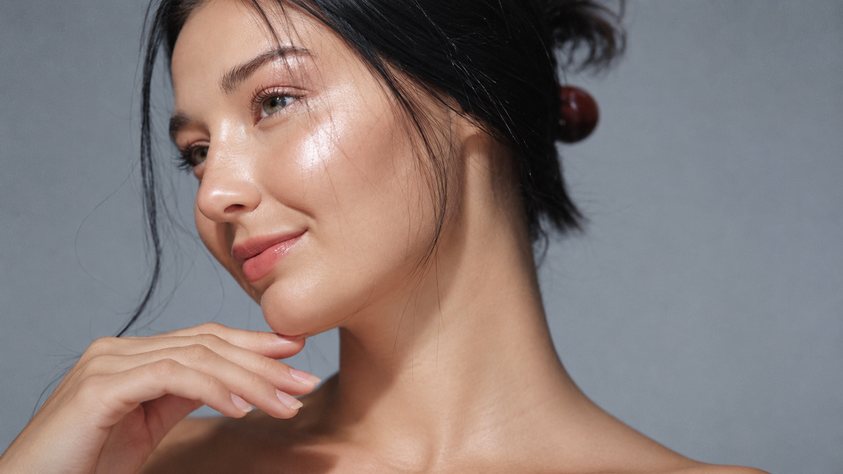 Portrait d'une femme brune à la peau lumineuse, main près du visage, soin Neostrata de Biostem