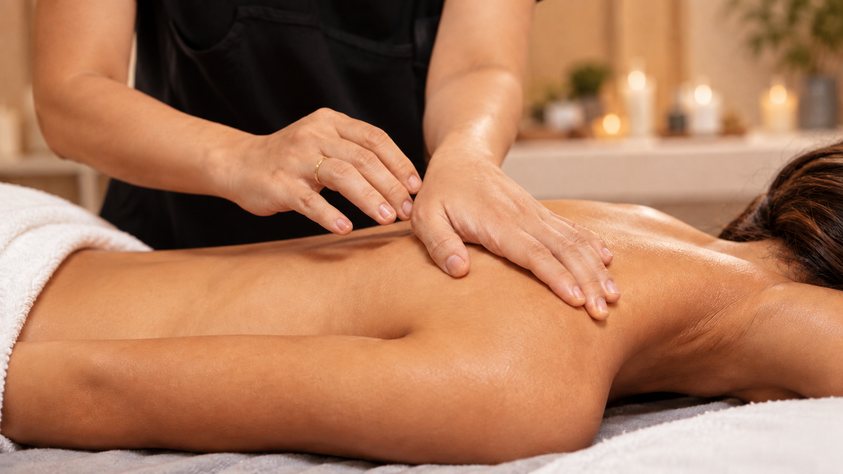 Mains posées sur le dos d'une femme allongée, soin Rééquilibrage de Biostem