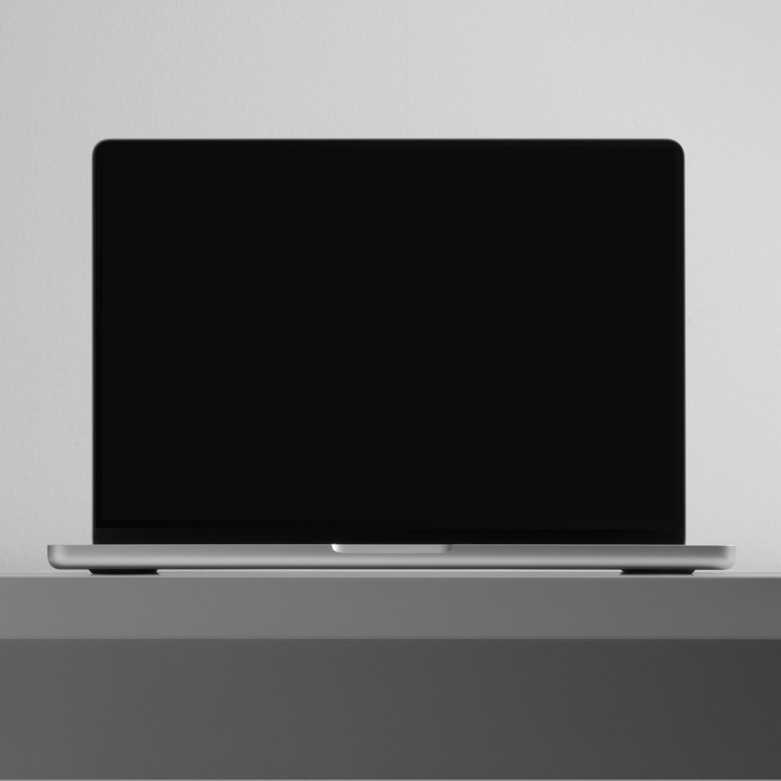 Ordinateur portable ouvert, écran noir, posé sur un socle gris clair : support des maquettes de sites